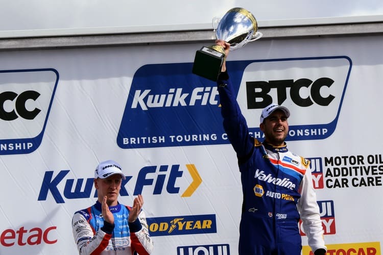 Motorsport podium image of man holding up a large silver trophy