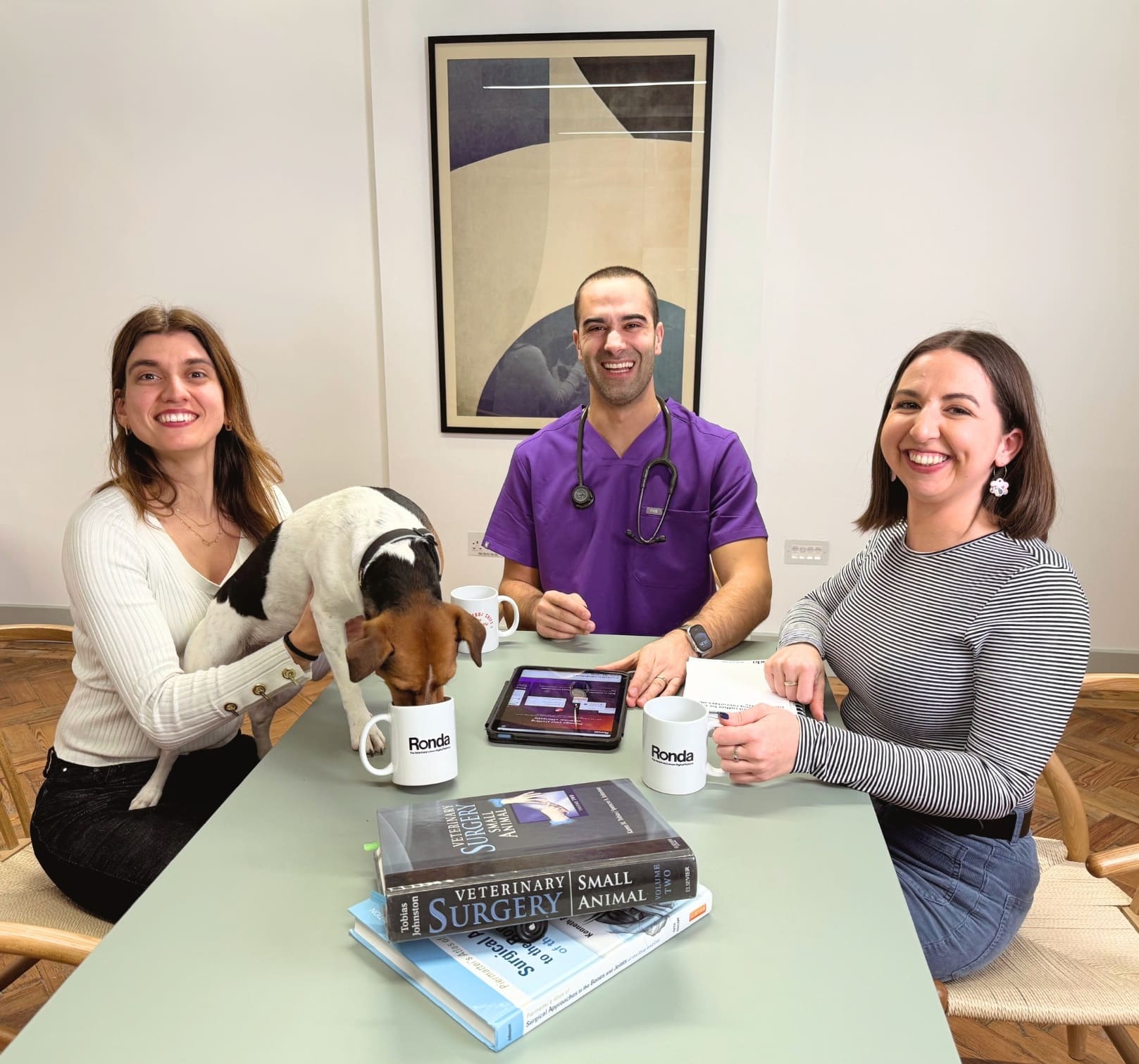 The Ronda.vet team pictured with dog drinking out of a mug