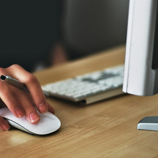 Someone using a mouse and laptop at a desk