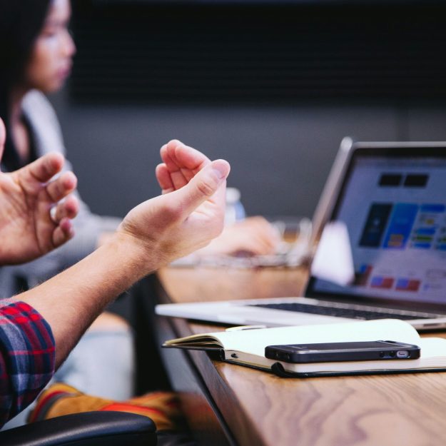 Someone talking in a meeting in front of a laptop